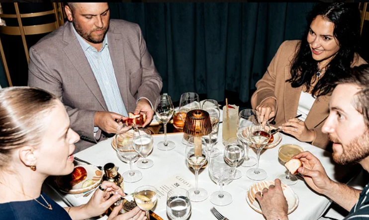 a group of people sitting at a table with food and drinks at Gatsby's calgary - new restaurant
